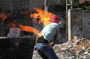 Palestinian protesters put out a fire burning on a compatriot, caused by a molotov cocktail which he was trying to hurl at Israeli troops during clashes in the West Bank city of Hebron, October 13, 2015. 